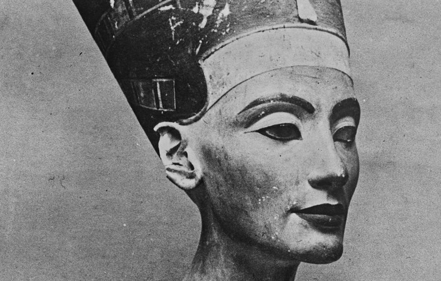 هذه صورة لتمثال نصفي لملكة أو إلهة مصرية قديمة، يُعتقد أنها نفرتيتي. يظهر التمثال النصفي بتفاصيل دقيقة وجميلة للوجه، بما في ذلك ملامح وجه متوازنة وعينين معبرتين. ترتدي الملكة تاجًا مميزًا مزينًا بتفاصيل دقيقة، بالإضافة إلى عقد رائع حول رقبتها. يُظهر التصميم دقة فنية تعكس الثقافة والفن المصري القديم.