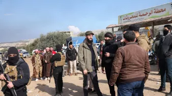 تظهر الصورة مجموعة من الأشخاص في منطقة مفتوحة تحت سماء زرقاء مع بعض الغيوم. يبدو أن هناك عددًا من الرجال يرتدون ملابس تقليدية وبعضهم يرتدي ملابس عسكرية أو شبه عسكرية. في الخلفية، يوجد لافتة تشير إلى "محطة الرحمة للمشاريع". يُلاحظ أن بعض الأشخاص يتحدثون مع بعضهم البعض، وهناك أيضًا مجموعة من الأشخاص يحملون أسلحة. الأجواء تبدو نشطة وتعبر عن تفاعل اجتماعي بين الحضور.