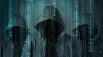 الصورة تظهر ثلاثة أشخاص يرتدون هوديات (أغطية رأس) سوداء، وجوههم غير مرئية. خلفهم يوجد تدرجات من الألوان الزرقاء تشبه البيانات الرقمية المتساقطة، مما يعطي انطباعًا عن بيئة إلكترونية أو تكنولوجية. الأجواء العامة للصورة توحي بالغموض أو الإخفاء.