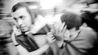 تظهر الصورة رجالاً يتجهون بسرعة في مشهد مزدحم، حيث يبدو أنهم في حالة من الحركة العفوية. الملابس التي يرتدونها متنوعة، ومن الواضح أن هناك نوعاً من التوتر أو الاضطراب في الوضع. الخلفية غير واضحة بسبب الضبابية، مما يعكس شعوراً بالسرعة أو الارتباك. الأربعاء وشعاراتهم تظهر تشويشاً في المشهد، مما يضيف إلى الديناميكية العامة للصورة.