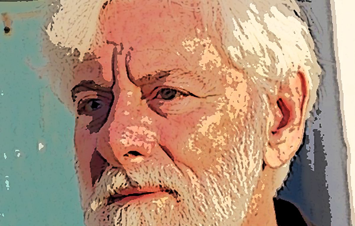 این تصویر یک مرد با موهای سفید و ریش خاکستری را نشان میدهد. او به سمت چپ نگاه میکند و facial expression او جدی و متمرکز است. پسزمینه شامل دیواری با رنگ آبی یا سبز است که ظاهری قدیمی دارد. لباس او تیره و ساده است، و به طور کلی تصویر حس آرامش و تفکر عمیق را منتقل میکند.