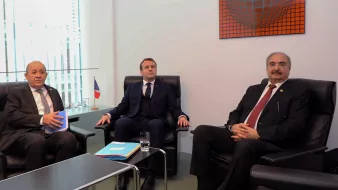 در این تصویر سه نفر نشستهاند. یکی از آنها در سمت چپ یک مرد با موهای خاکستری و در حال صحبت است. در وسط، مردی با کت و کراوات تیره نشسته که به نظر میرسد به موضوعی توجه میکند. شخص سوم در سمت راست یک مرد با موهای سیاه و چهرهای جدی است که او نیز در حال حاضر در نشستی قرار دارد. پسزمینه تصویر شامل پنجرههایی است که نور طبیعی را به اتاق وارد میکند. در کنار این افراد، پرچمی از فرانسه به چشم میخورد.