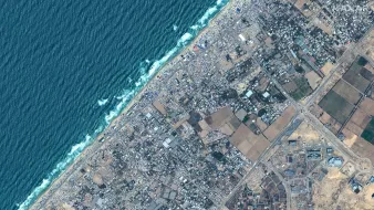 این تصویر یک نمای هوایی از ناحیهای است که شامل سواحل و مناطق مسکونی و کشاورزی میباشد. در سمت چپ تصویر، یک نوار آبی رنگ نمایان است که به دریا اشاره دارد، در حالی که در سمت راست، زمینهای کشاورزی و ساختمانهای مسکونی وجود دارند. بافت شهری به صورت متراکم و پراکنده دیده میشود و همچنین برخی مناطق سبز و زمینهای زراعی نیز در پایین تصویر مشخص است.