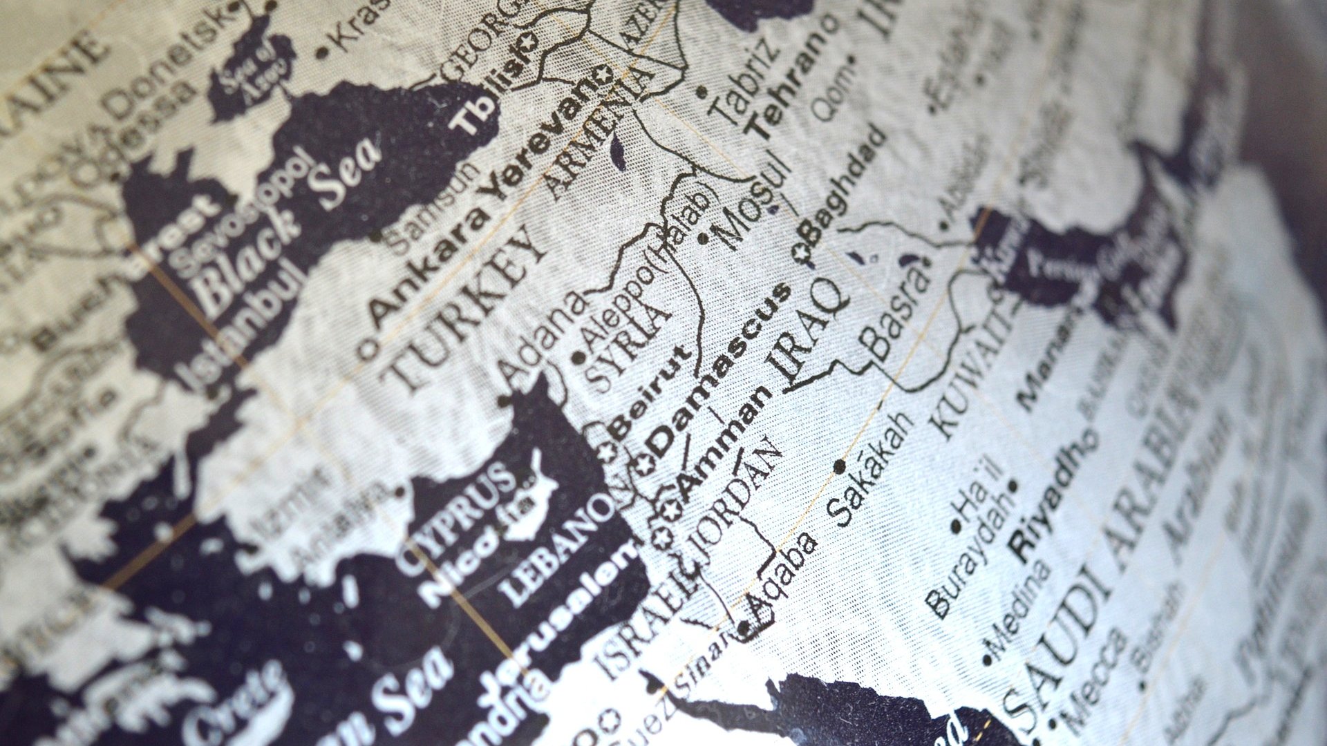 L'image montre une carte en noir et blanc d'une région qui inclut le Moyen-Orient et certaines parties de l'Europe et de l'Asie. On peut distinguer des pays comme la Turquie, l'Iran, l'Irak et l'Arabie Saoudite. Les noms des villes et des pays sont inscrits en lettres claires, créant un contraste avec le fond noir. La carte semble stylisée, donnant une impression de vintage ou d'art graphique.