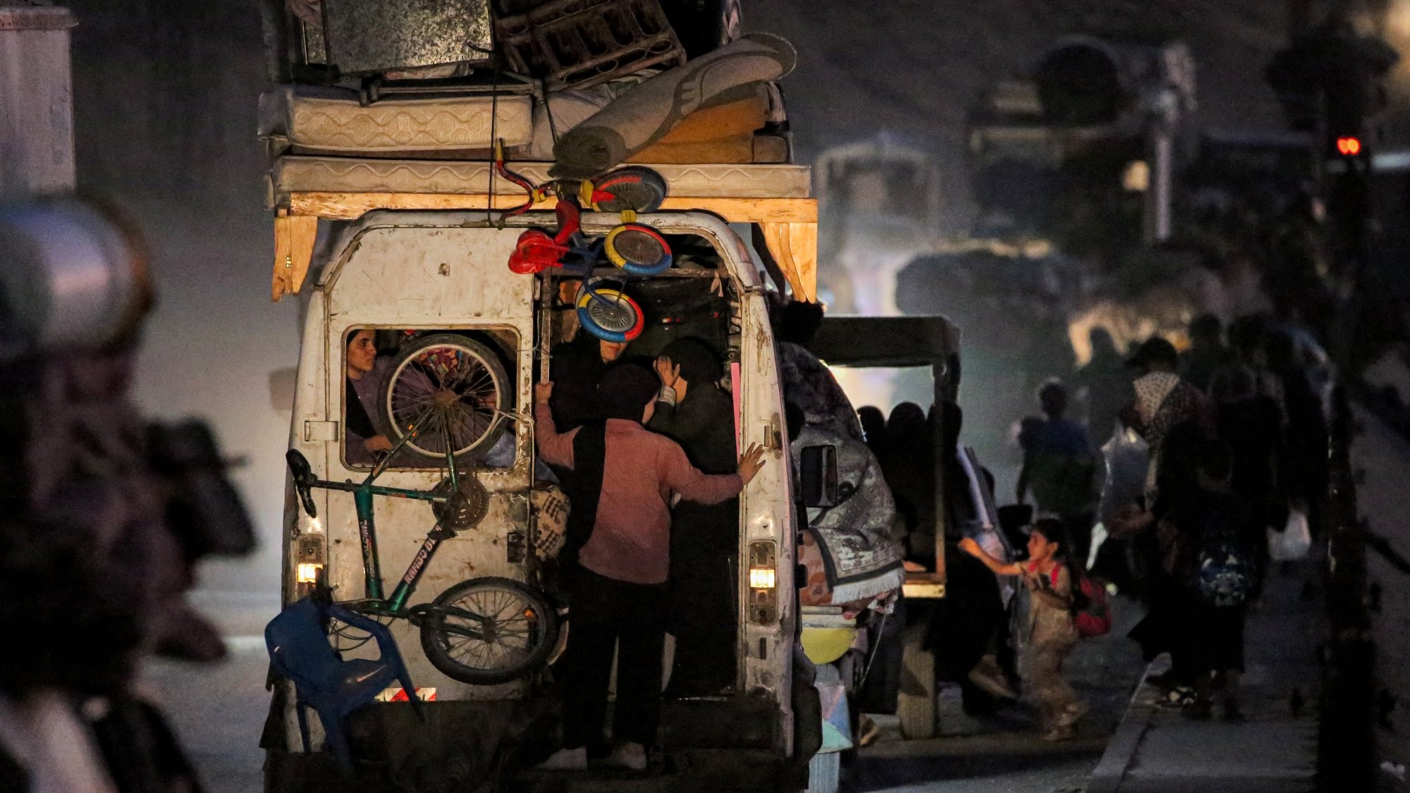 Gens chargent des marchandises dans un véhicule, ambiance nocturne et mouvement.