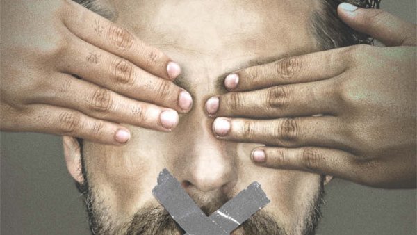 L'image représente un homme avec une barbe qui a les yeux couverts par des mains. Son visage affiche une expression sérieuse et déterminée. Sur sa bouche, il y a une croix qui symbolise le silence, tandis qu'en dessous, on peut lire en lettres majuscules "JOURNALISM IS NOT A CRIME" (Le journalisme n'est pas un crime) et le hashtag "#FREEAJSTAFF". L'ensemble de l'image semble véhiculer un message fort en faveur de la liberté de la presse et de la protection des journalistes.