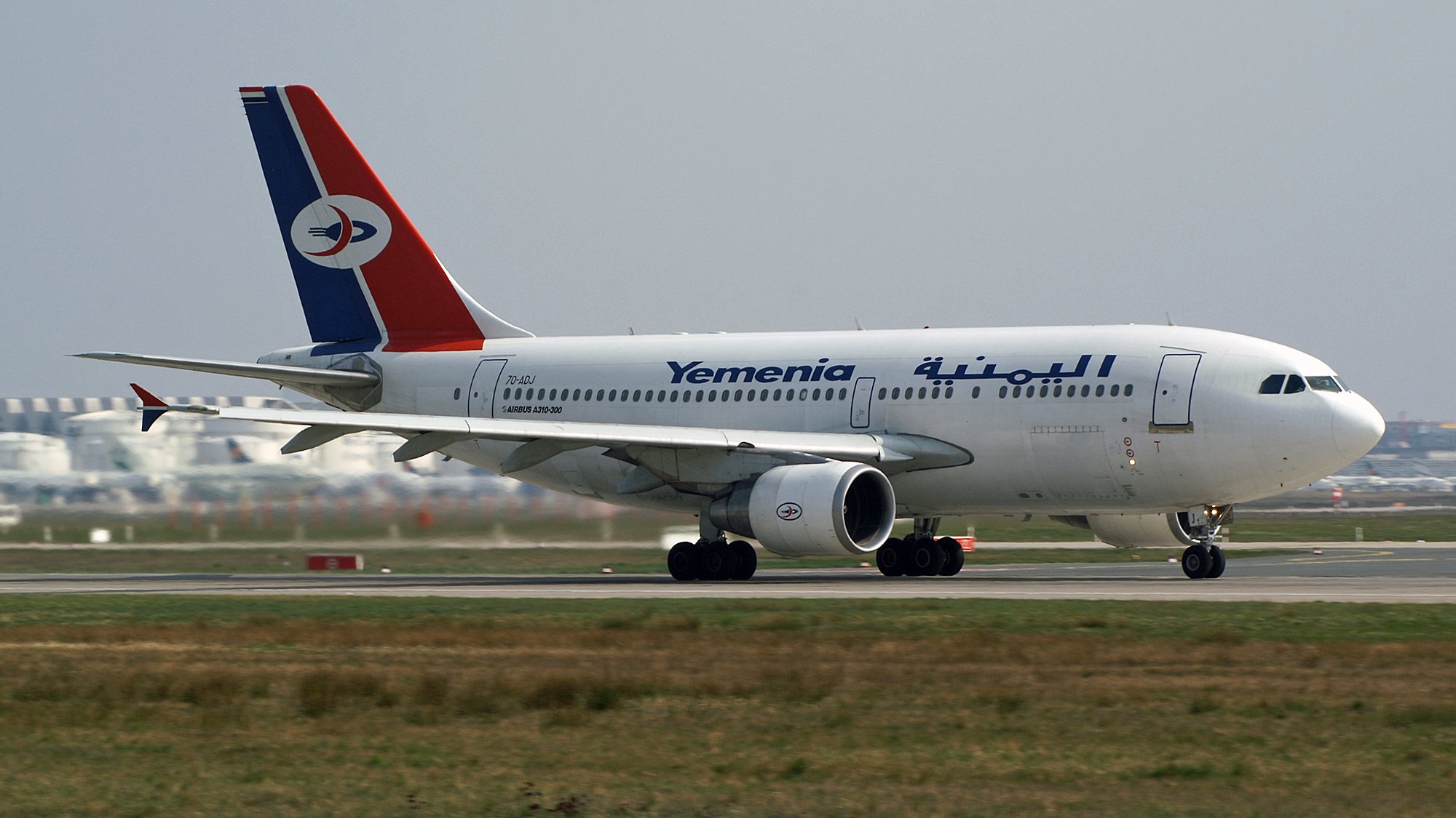 Avion de la compagnie Yemenia avec un design aux couleurs rouge, bleu et blanc sur la piste.