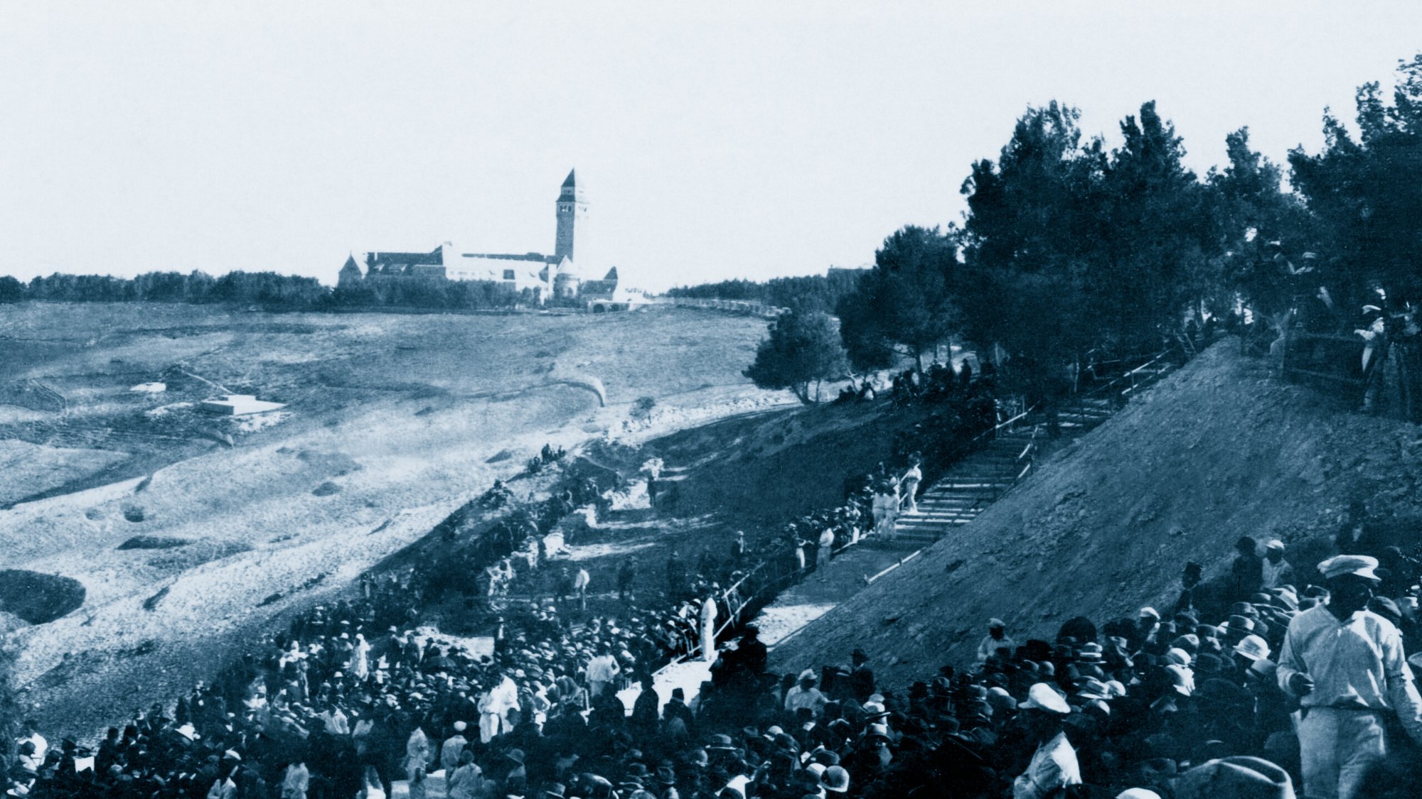 Une foule en bas d'une colline, avec un bâtiment en arrière-plan, scène historique.