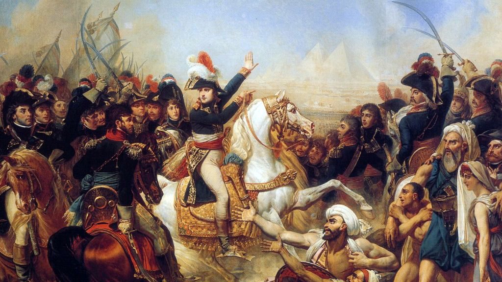 L'image représente une scène historique chargée d'émotions, probablement liée à la campagne d'Égypte de Napoléon Bonaparte. Au premier plan, Napoléon est sur un cheval blanc, vêtu de son uniforme militaire, semblant diriger ses troupes. On aperçoit des soldats français en uniforme, ainsi que des combattants locaux, ce qui indique un affrontement. À l'arrière-plan, les pyramides d'Égypte se dressent majestueusement, ajoutant une dimension emblématique à la scène. L'atmosphère est intense, reflétant le chaos et la violence de la bataille.