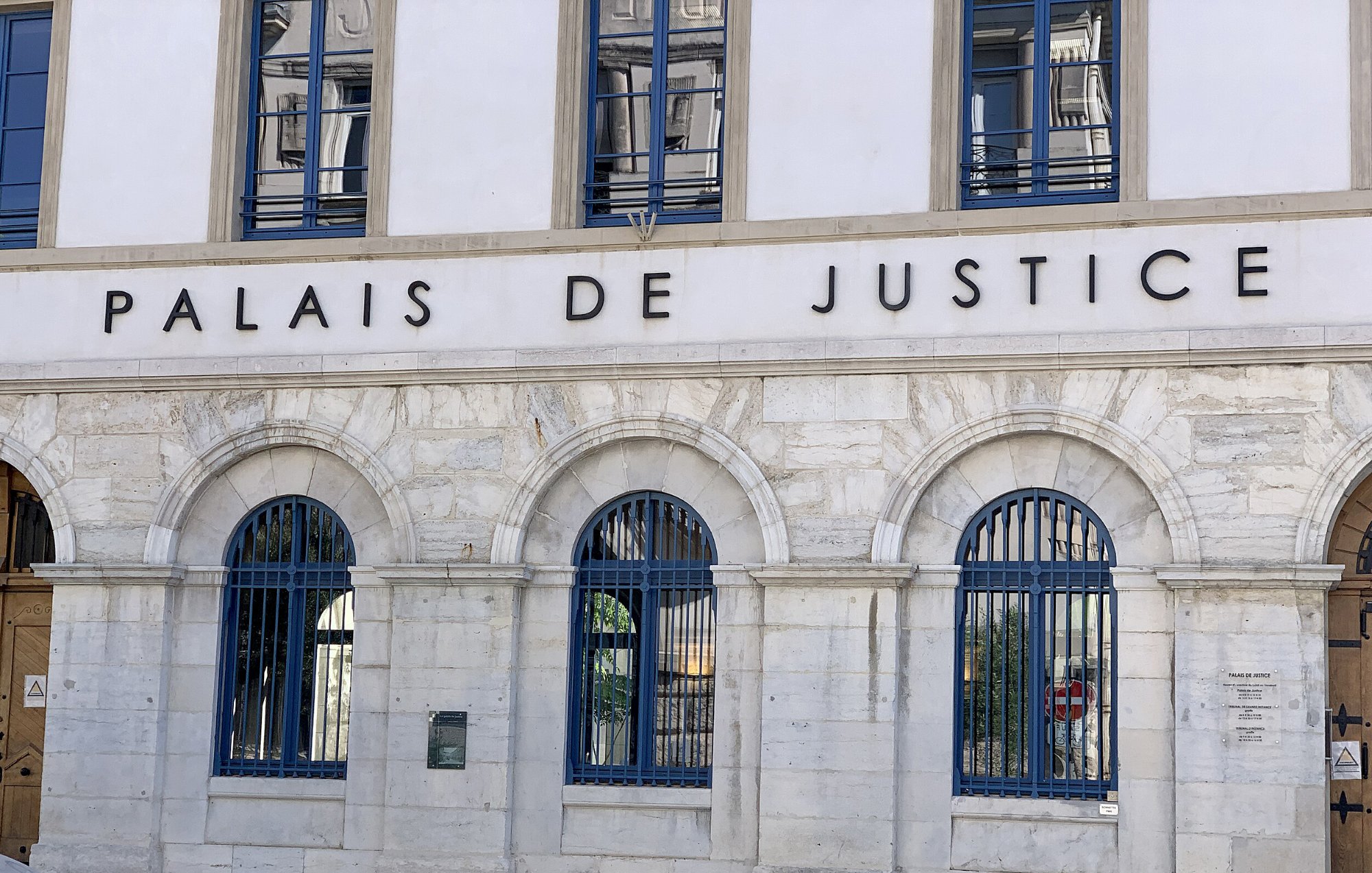 Façade d'un bâtiment imposant avec l'inscription "Palais de Justice" et des fenêtres à arcs.
