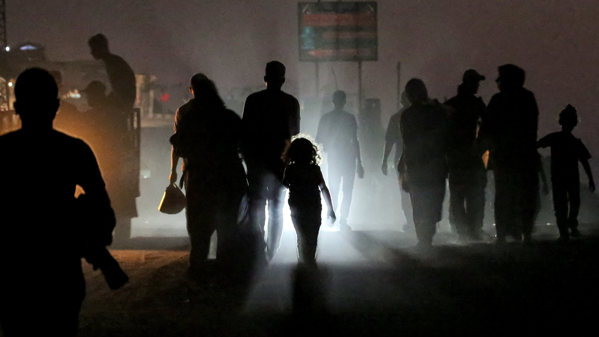 Silhouettes de personnes marchant dans une ambiance brumeuse, une enfant éclairée au centre.