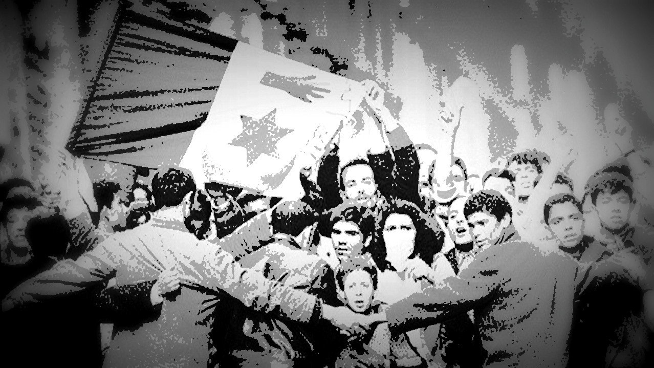 L'image montre une scène de rassemblement populaire où des manifestants brandissent une grande bannière ou un drapeau. Les participants semblent célébrer ou exprimer des revendications, et il y a une forte énergie collective. Certains visages sont visibles, reflétant diverses émotions, allant de la détermination à la joie. La composition en noir et blanc crée une atmosphère nostalgique et dramatique, soulignant l'importance historique de cet événement.