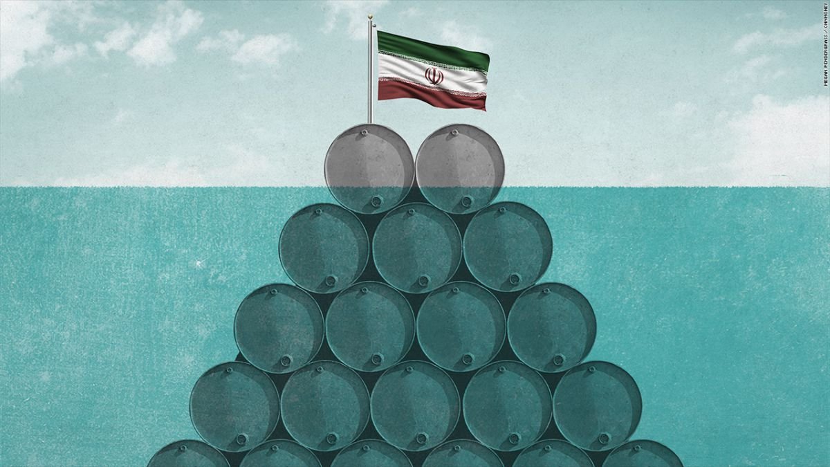 L'image représente une pyramide de barils de pétrole, avec un drapeau iranien posé au sommet. Les barils, disposés de manière à former une base solide, symbolisent potentiellement l'industrie pétrolière de l'Iran. En arrière-plan, un ciel légèrement nuageux donne une ambiance neutre à la scène. La combinaison de ces éléments peut suggérer des thèmes liés aux ressources naturelles, à l'économie ou à la politique énergétique.
