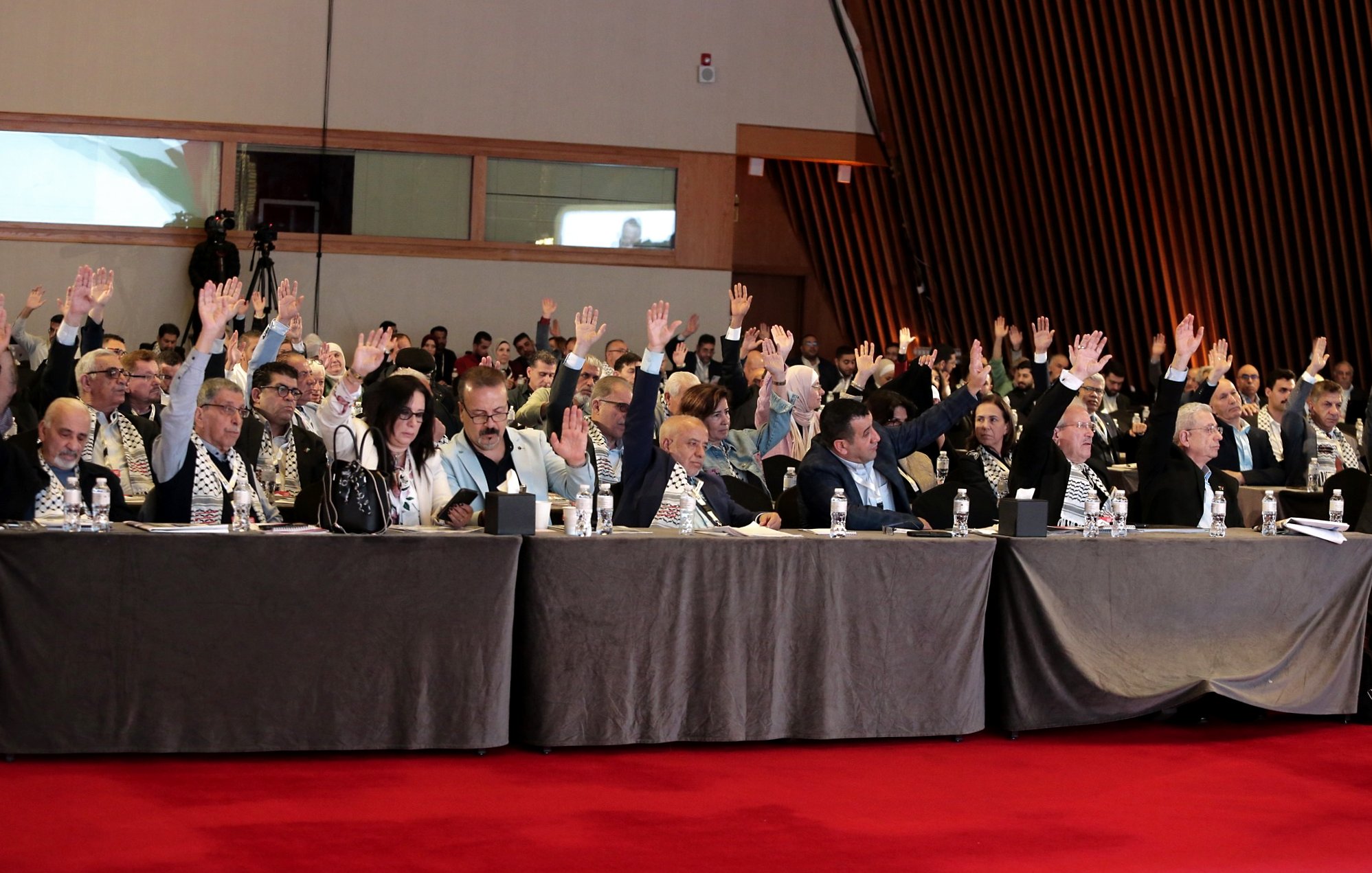 Salle de réunion avec des participants levant la main pour voter.