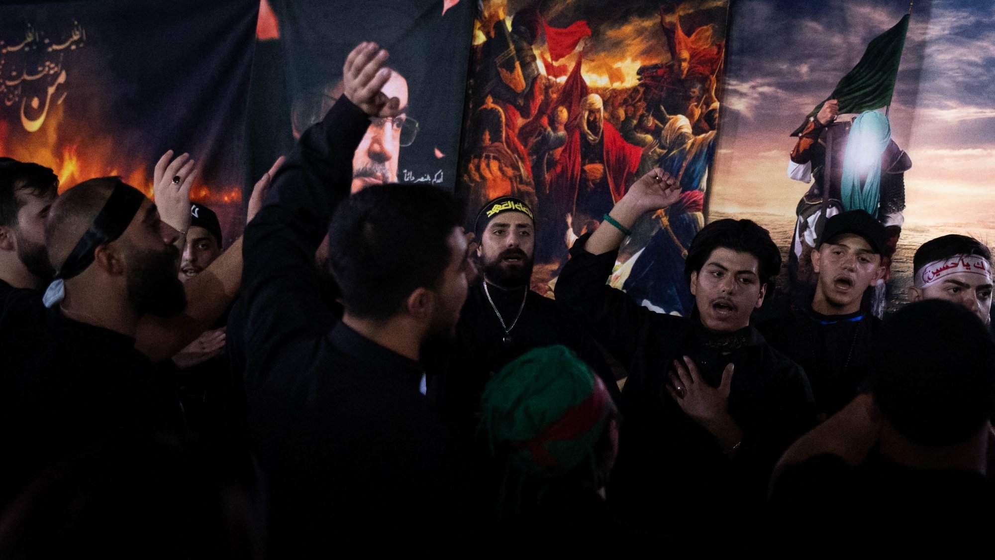 Des hommes en vêtements noirs chantent et montrent des signes de dévotion.