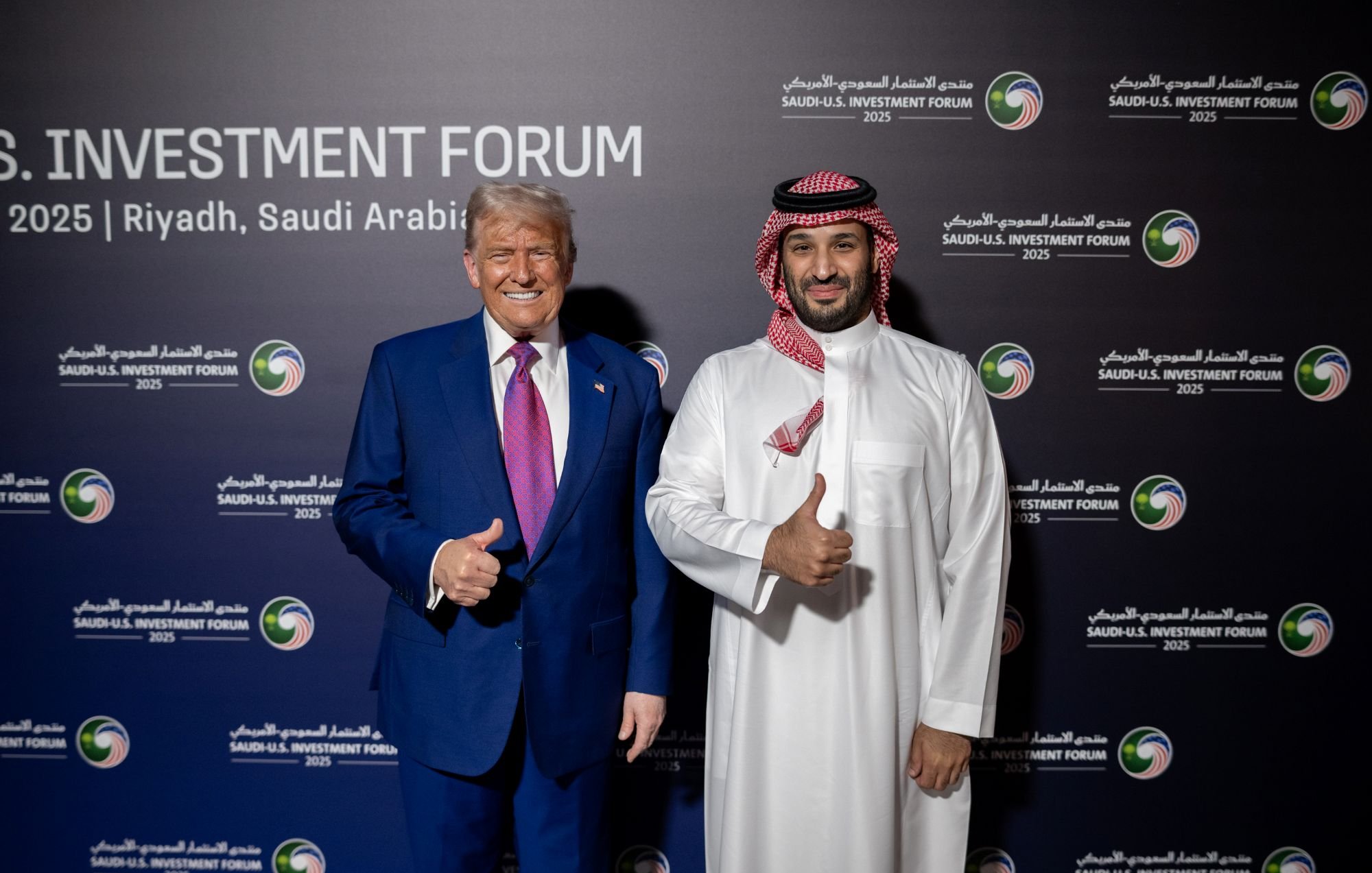 Deux hommes souriants, l'un en costume, l'autre en tenue traditionnelle, posent ensemble.