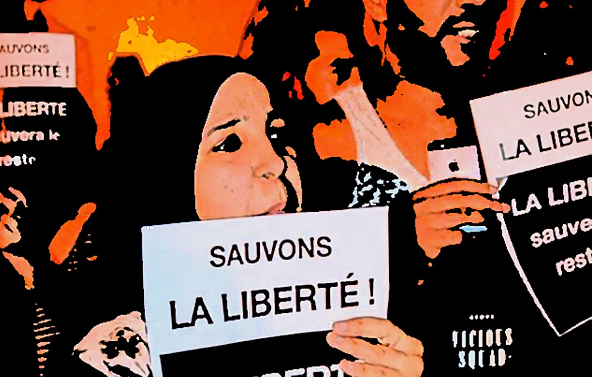 L'image montre un groupe de personnes tenant des pancartes sur lesquelles on peut lire "Sauvons la liberté !" et "La liberté sauvera le reste...". Il semble s'agir d'une manifestation ou d'un rassemblement pour défendre la liberté, avec des participants affichant des expressions engagées et déterminées. L'ambiance semble être à la mobilisation et à la solidarité.