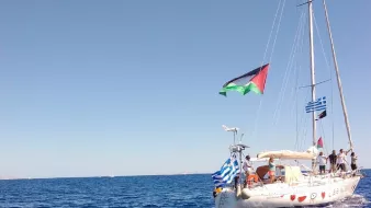 Un voilier sur la mer, arborant plusieurs drapeaux, sous un ciel bleu.