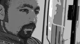 L'image présente un homme dont le visage est partiellement en ombres et lumières, ce qui donne une ambiance introspective. Il semble pensif, regardant dans une direction indéfinie. Les traits de son visage sont marqués, et il a une barbe bien entretenue. Le fond est flou, ce qui permet de concentrer l'attention sur son expression méditative.