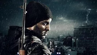 L'image présente un homme au regard déterminé, vêtu d'un bonnet et d'un manteau sombre. Il se tient de profil, tenant une arme à feu. En arrière-plan, on peut voir une ville sous une atmosphère sombre, avec des éclairs, suggérant une ambiance dramatique. Le titre en bas de l'image est écrit en arabe et semble évoquer un thème de lutte ou de conflit.