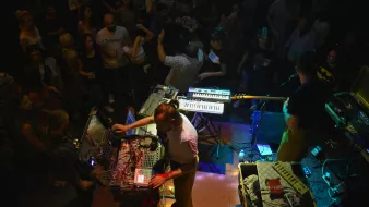 Concert animé avec des musiciens, des synthétiseurs et une foule dans une ambiance festive.