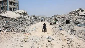 Un chemin au milieu des ruines, une personne en fauteuil roulant avance lentement.