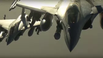 L'image montre plusieurs avions de chasse, probablement des Rafales, en formation dans le ciel. Les avions sont affichés de profil, mettant en valeur leur design aérodynamique. On peut observer leurs ailes, leurs moteurs et les divers équipements militaires qui les équipent. Le ciel semble clair, ce qui permet une bonne visibilité des avions. L'ensemble donne une impression de puissance et de précision technologique.