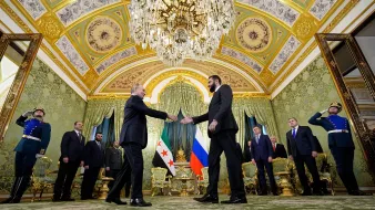 Réunion officielle dans une salle luxueuse, avec des drapeaux et des personnes en uniforme.