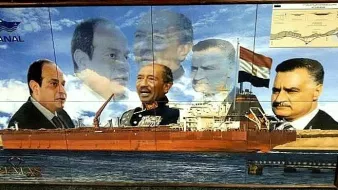 L'image présente une fresque murale qui montre un grand cargo au premier plan, naviguant sur l'eau. En arrière-plan, plusieurs portraits en superposition de différentes figures politiques égyptiennes, évoquant probablement des présidents ou dirigeants historiques. L'ensemble crée une composition qui semble célébrer l'histoire maritime et politique de l'Égypte, en particulier autour du canal de Suez. Des éléments graphiques comme le logo du canal et une carte en haut à droite ajoutent au contexte maritime.