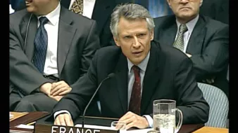 Homme en costume, sérieux, représentant la France lors d'une réunion officielle.