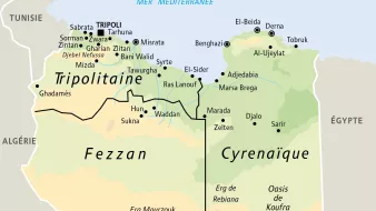 L'image représente une carte de la Libye, divisée en trois régions principales : la Tripolitaine, le Fezzan et la Cyrénaïque. On peut y voir les principales villes telles que Tripoli, Misrata, Benghazi et Tobrouk, ainsi que des routes importantes. Les limites géographiques des différentes régions sont clairement marquées, et la mer Méditerranée est indiquée au nord. Des éléments topographiques comme les déserts et les oasis sont également présents sur la carte.