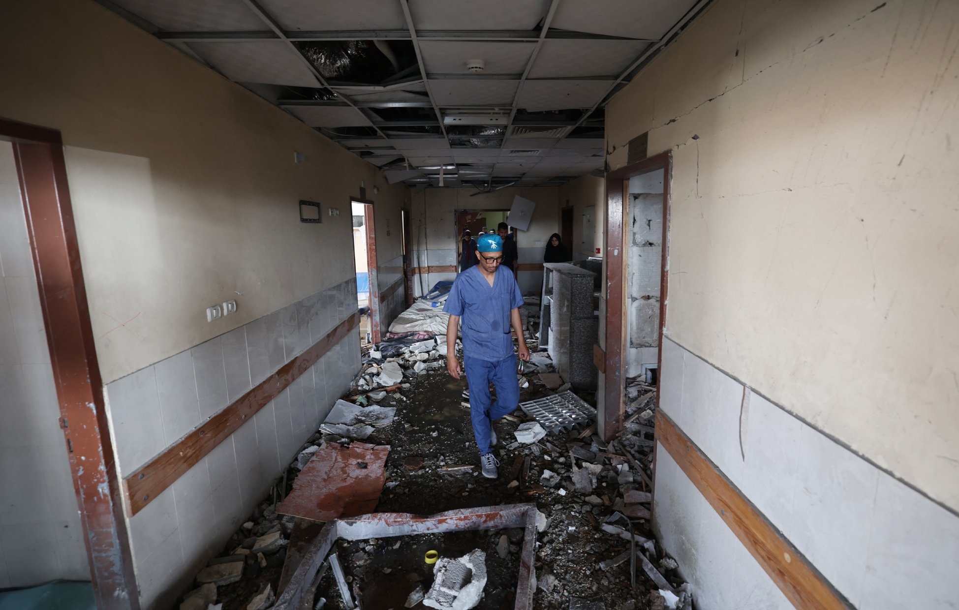 Un uomo in un corridoio distrutto, con macerie e soffitto danneggiato.