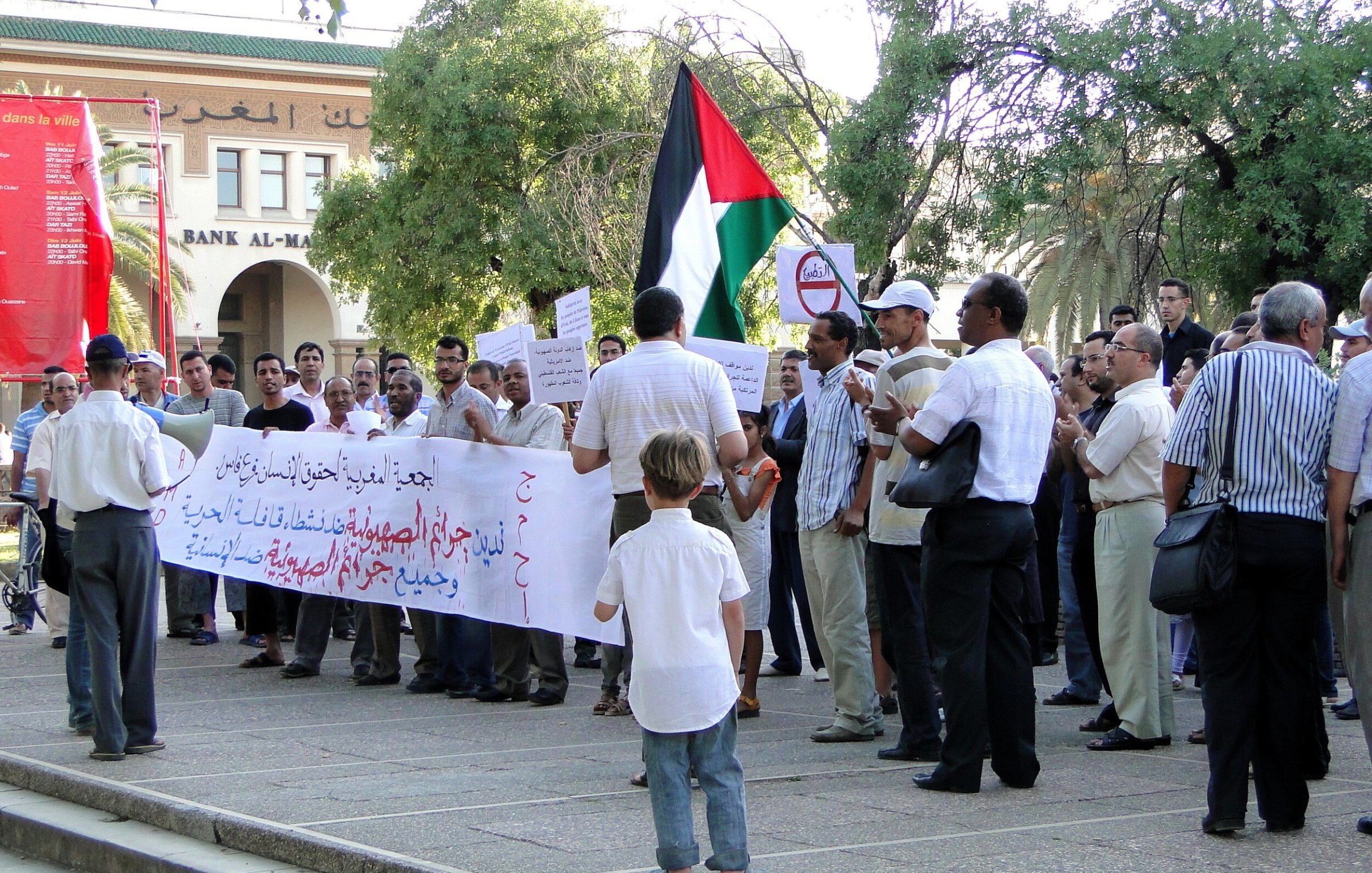 Un gruppo di persone in protesta con bandiera palestinese e striscioni.