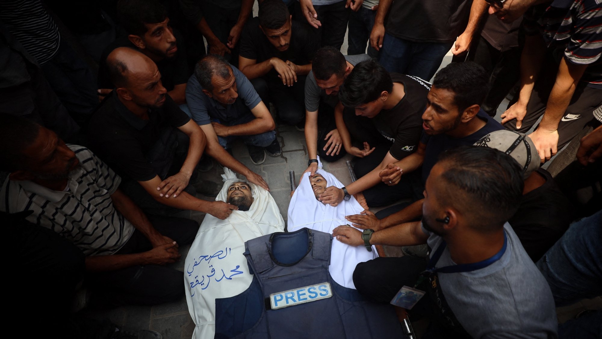 Un gruppo di persone attorno a un corpo coperto, in segno di lutto e protesta.