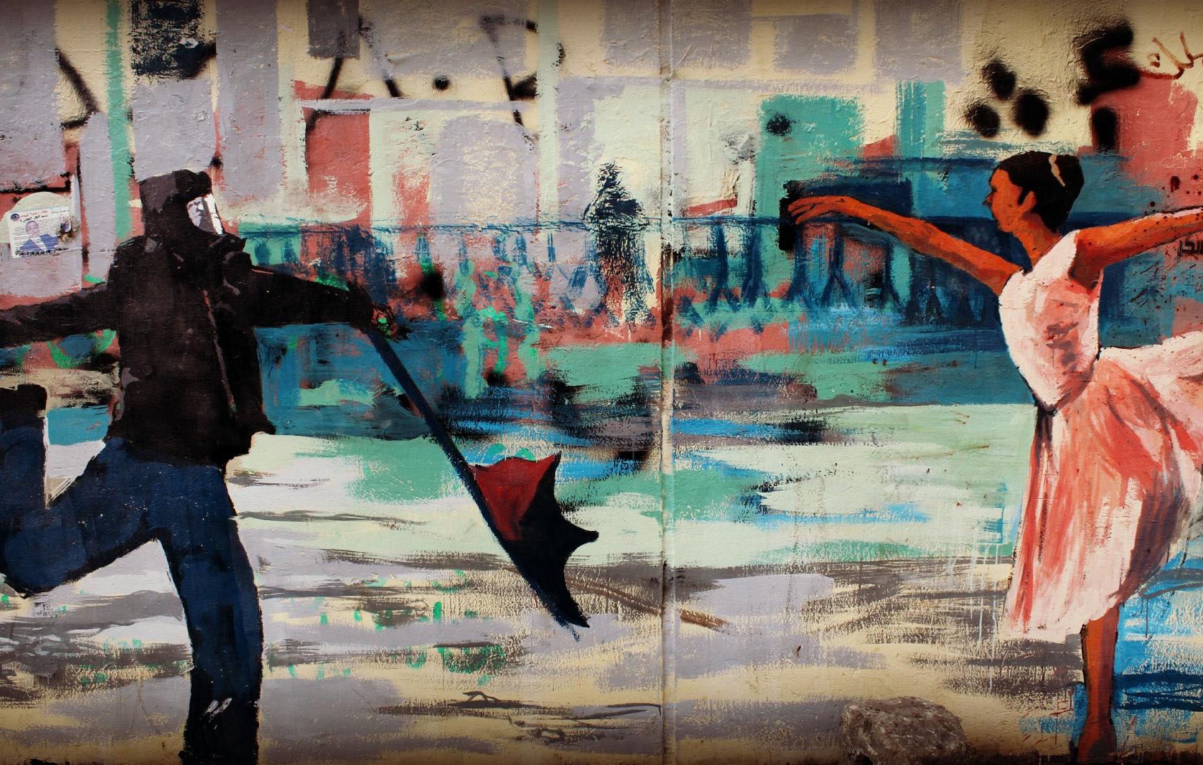 L'immagine mostra un murales che raffigura una scena dinamica e contrastante tra due figure. A sinistra, c'è una persona vestita con abiti scuri e un cappuccio, che tiene un ombrello mentre sembra quasi essere in movimento, con una gamba sollevata come se stesse per fare un passo danzante. A destra, c'è una ballerina vestita in un abito chiaro, probabilmente una tutù da danza classica, che si trova in una posa elegante con una gamba alzata all'indietro e le braccia aperte. Lo sfondo è astratto, con colori vivaci e pennellate ampie che suggeriscono edifici e una scena urbana. Il contrasto tra lo stile di abbigliamento scuro e casual del primo personaggio e la grazia e la leggerezza della ballerina crea un'immagine ricca di movimento e significato.