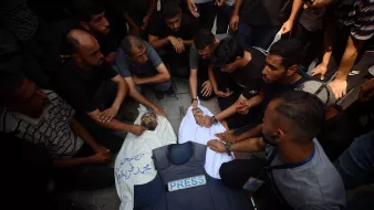 Un gruppo di persone attorno a un corpo coperto, in segno di lutto e protesta.