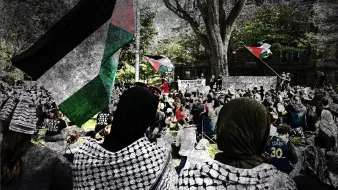L'immagine mostra una manifestazione in cui partecipano molte persone, alcune delle quali indossano sciarpe tradizionali palestinesi. Si possono vedere delle bandiere palestinesi sventolare sullo sfondo. La scena è caratterizzata da una grande affluenza di partecipanti, con un'atmosfera di attivismo e solidarietà. Gli alberi e l'architettura circostante forniscono un contesto urbano alla manifestazione, suggerendo un forte impegno per una causa sociale.