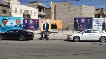 Una strada con diversi manifesti pubblicitari colorati su un muro di fondo.