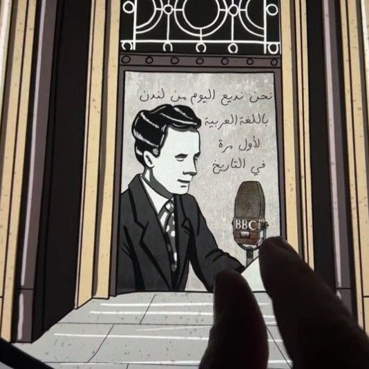 The image features an artistic representation of a historical figure, likely a broadcaster or writer, positioned near a prominent entrance, possibly of a building associated with the BBC. In the background, there are decorative elements and text, which could be in Arabic, hinting at cultural significance. A finger reaches towards a vintage microphone marked with "BBC," suggesting an interaction with the image or a focus on the broadcasting element. The overall style appears to be a blend of illustration and graphic design, emphasizing both history and media.