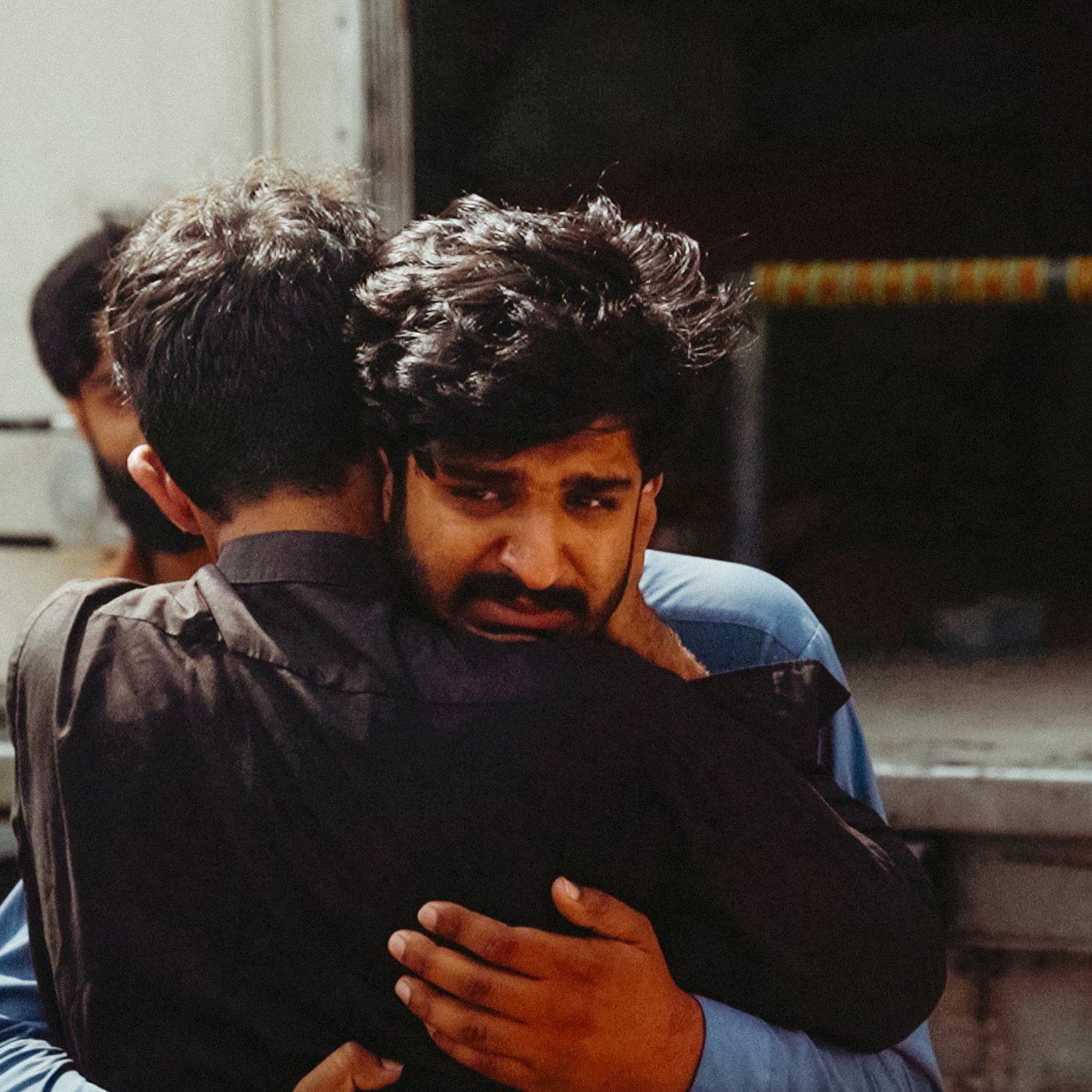 Deux hommes s'étreignent, l'un montre une profonde tristesse.