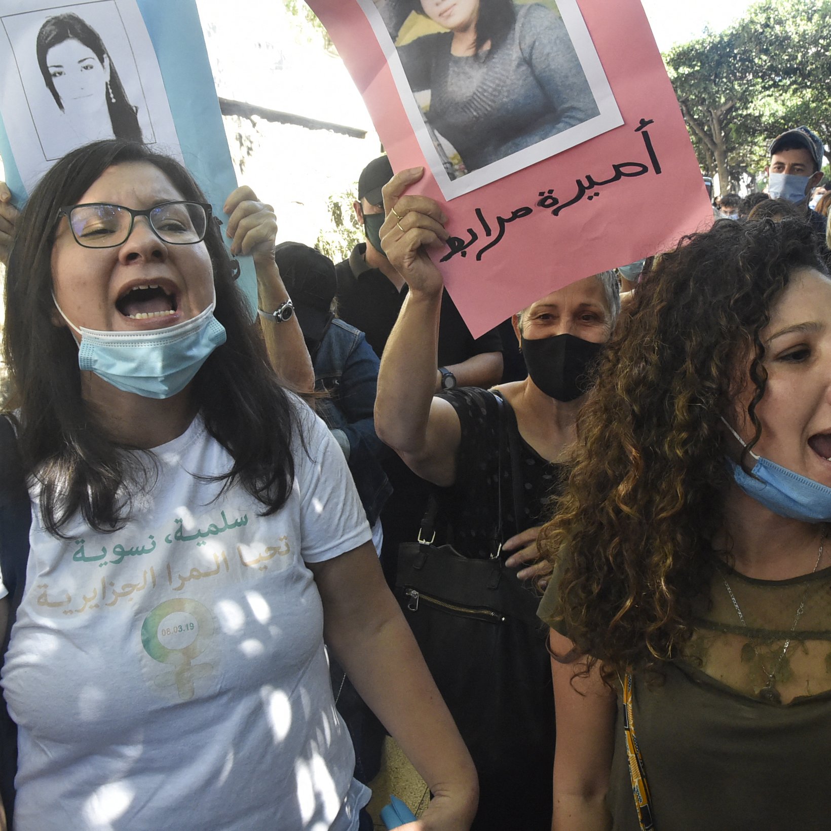 تظهر الصورة مجموعة من المتظاهرين في مظاهرة، حيث يحمل البعض لافتات وصور لأشخاص. يبدو أن الحضور متحمسون ويرفعون أصواتهم تعبيرًا عن رأي أو موقف معين. بعض الأشخاص يرتدون كمامات، مما يشير إلى حرصهم على اتخاذ تدابير وقائية. الأجواء تعكس العاطفة والقوة في التعبير عن مطالبهم.