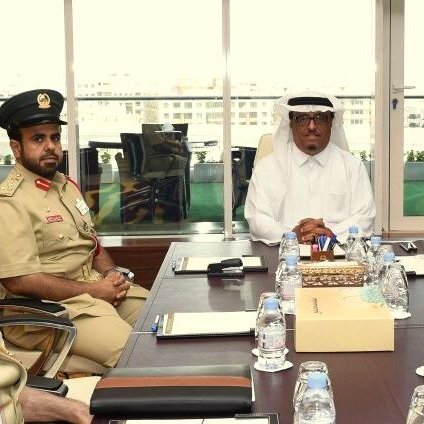 تظهر الصورة مجموعة من الرجال الذين يرتدون زيًا رسميًا في اجتماع. يجلس شخصان على اليسار يرتديان زياً عسكرياً، بينما يجلس الشخص الثالث على اليمين مرتديًا ثوبًا أبيض وعقال. يبدو أنهم يتناقشون حول موضوع مهم، حيث تركز الكاميرا على تعبيراتهم الجادة. في الخلفية، نلاحظ نوافذ كبيرة تُظهر منظرًا خارجيًا، مما يعكس طبيعة المكان وأجواء الاجتماع.