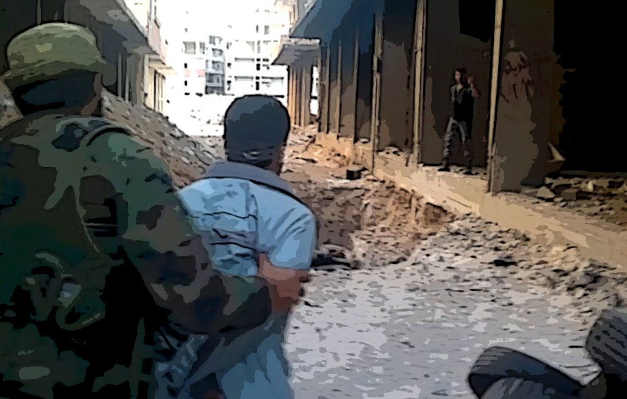 The image depicts a war-torn urban environment. A soldier in military attire is seen guiding or restraining a person wearing a light-colored shirt. The setting suggests destruction, with debris scattered on the ground and the remnants of buildings in disrepair. In the background, another individual is partially visible, possibly further down the street. The overall atmosphere conveys a sense of tension and conflict.