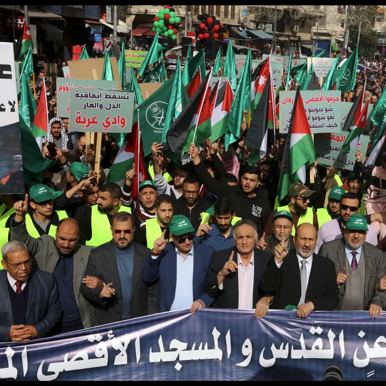 تظهر الصورة مظاهرة حاشدة تحمل الأعلام واللافتات، تعبر عن دعم للقضية الفلسطينية.