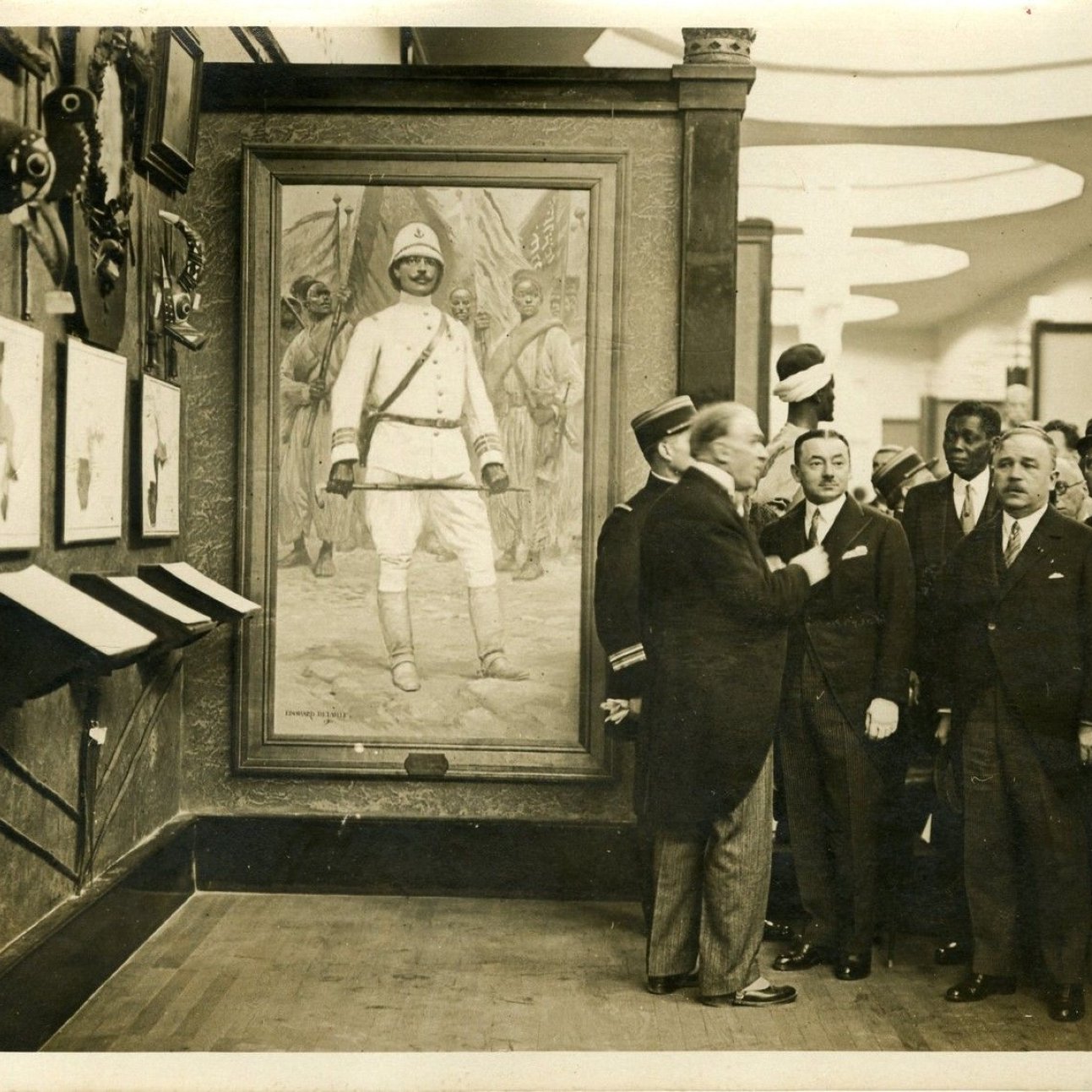 Des hommes en costume admirent un tableau d'un soldat dans un musée.