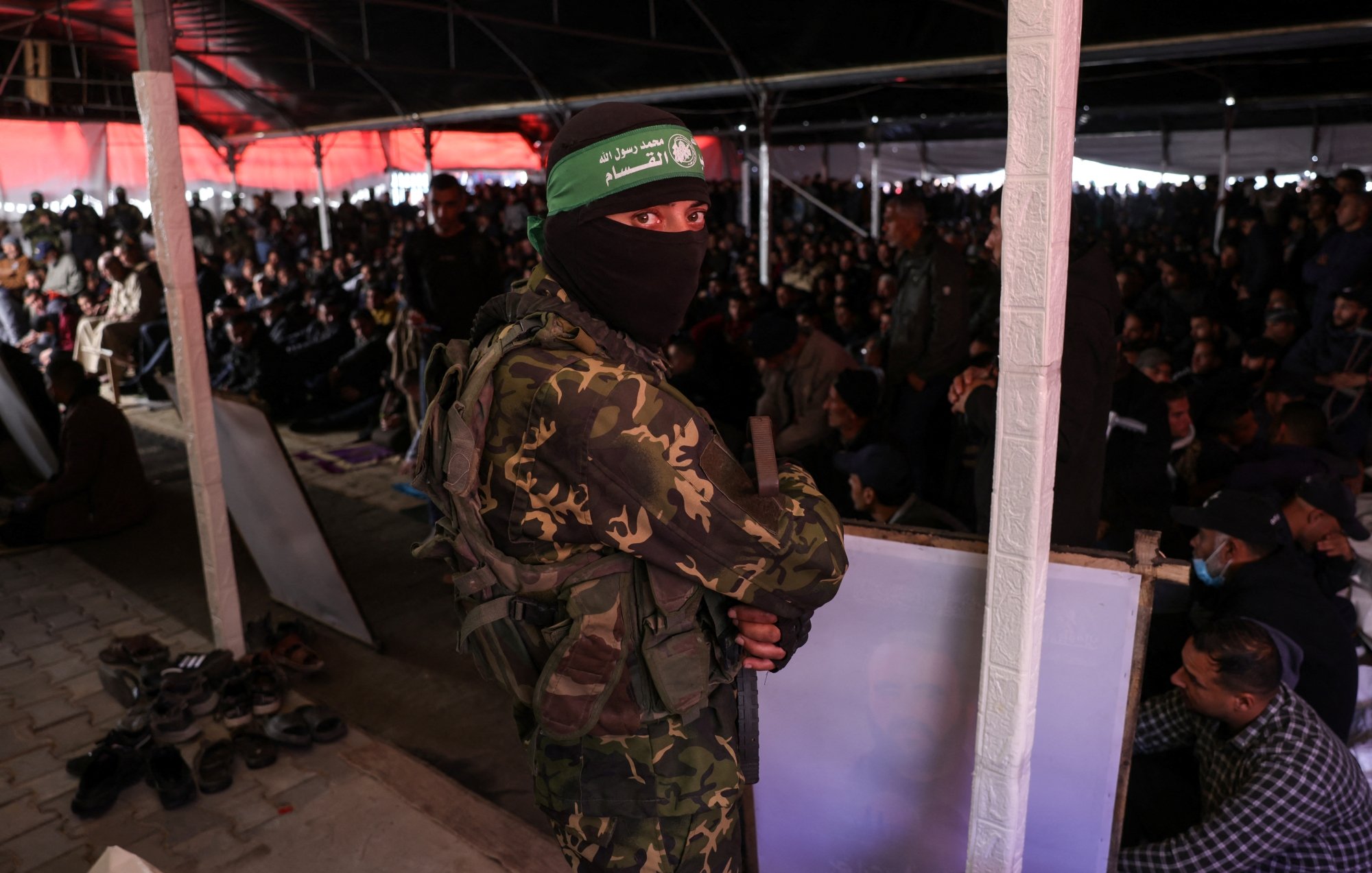 Un soldat masqué en uniforme surveille une grande foule au sein d'un bâtiment.