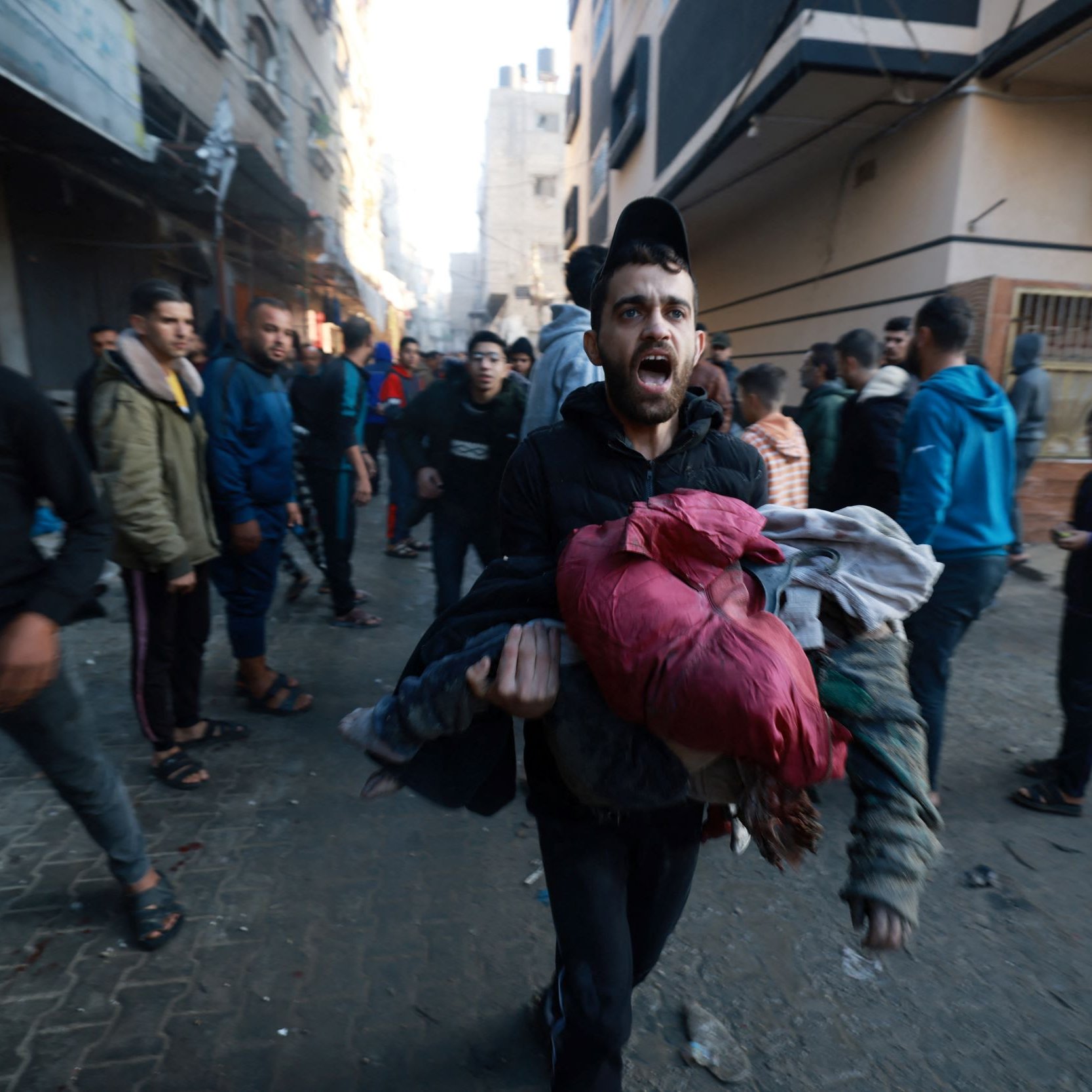 در این تصویر، گروهی از مردم در یک خیابان مشغول حرکت هستند، به نظر می‌رسد که موقعیت اضطراری یا بحرانی وجود دارد. یک مرد در حال دویدن است و چندین لباس را در آغوش گرفته است. چهره او حاکی از اضطراب و نگرانی است. دیگر افراد نیز در حال حرکت هستند و فضای خیابان به نظر شلوغ و پر از فعالیت است. ساختمان‌ها در پس‌زمینه نشان‌دهنده یک محیط شهری هستند.