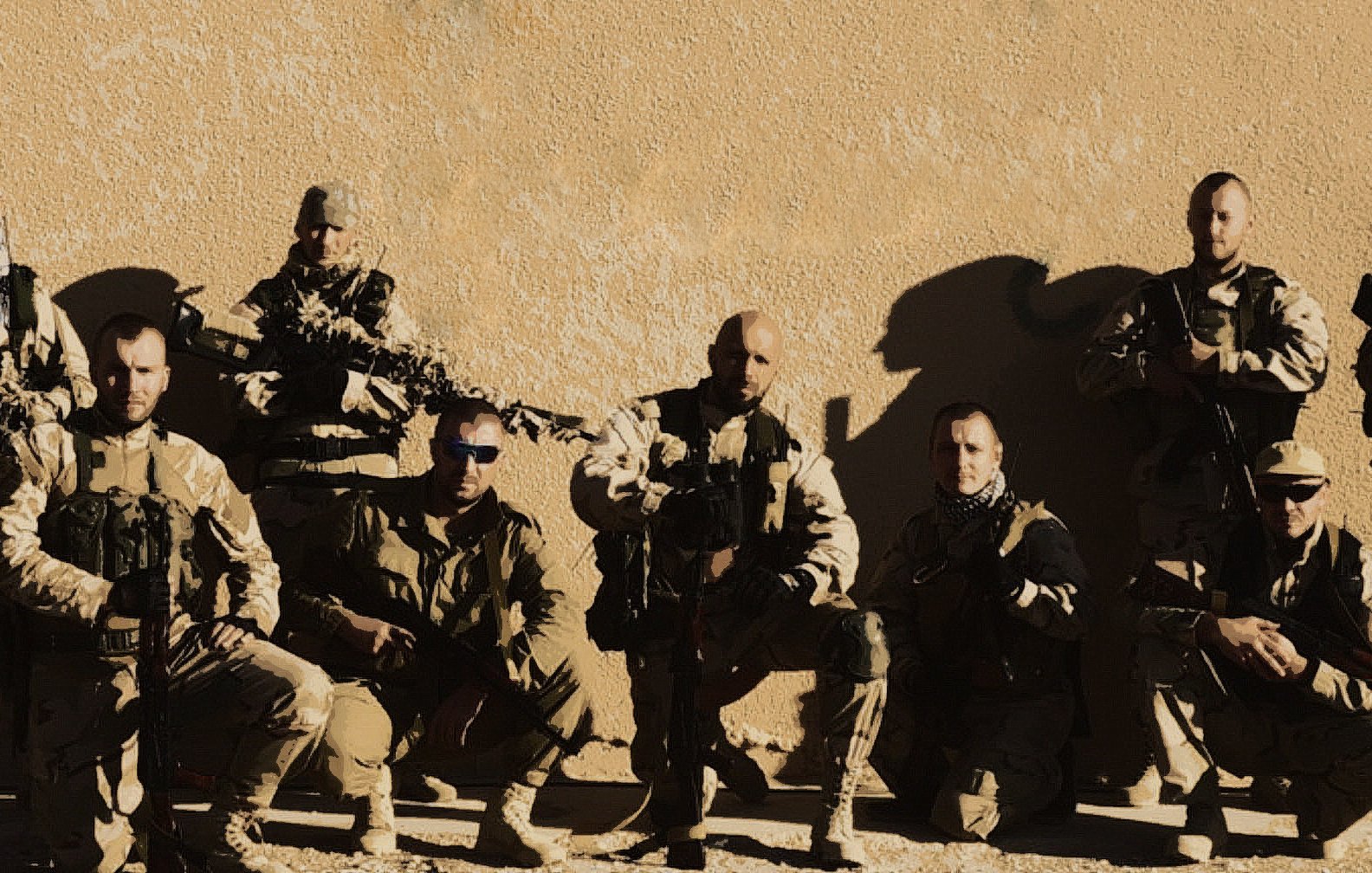 الصورة تظهر مجموعة من الجنود أو أفراد القوات المسلحة، يقفون معًا في وضعية تعكس القوة والانضباط. يرتدون زيًا عسكريًا ويحملون أسلحة، ويظهرون بمظهر جاد. الخلفية تبدو بسيطة، مما يركز الانتباه على المجموعة. تعكس الصورة روح الفريق والتضامن بين الأفراد.