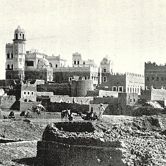 این تصویر نشان‌دهنده‌ی یک منطقه تاریخی است که در آن ساختمان‌های قدیمی با معماری سنتی دیده می‌شوند. در پس‌زمینه، چندین ساختمان با سقف‌های گنبدی و تزئینات خاص وجود دارد. همچنین افرادی در حال کار در زمین‌های جلویی دیده می‌شوند که ممکن است مشغول کشاورزی یا ساخت‌وساز باشند. این صحنه، حال و هوای زندگی روزمره و تاریخی را در یک جامعه قدیمی به تصویر می‌کشد.