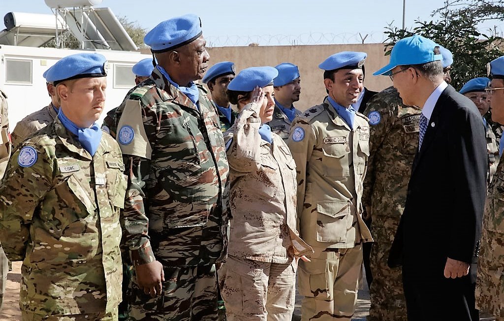 تظهر الصورة مجموعة من الأفراد العسكريين يرتدون بزات الأمم المتحدة الزرقاء، ويبدو أنهم في موقع رسمي. يوجد شخص يحاول التحية، في حين يبدو أن هناك اجتماعًا أو زيارة يقوم بها أحد الشخصيات المهمة. المجموعة تشمل أفرادًا من خلفيات عسكرية متنوعة، ويبدو أن هناك تواصلًا ونقاشًا بينهم. الجو العام يبدو جادًا ومهنيًا، وربما يشير إلى مهمة سلمية.